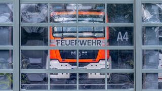 Ein Feuerwehrauto hinter einem Glastor. (Symbolbild) Im Landkreis Konstanz werden Rettungskräfte zukündtig digital alarmiert.