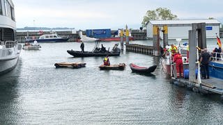 Rettungskräfte sichern Floße und Kanu im Hafen von Friedrichshafen