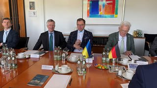 Yuriy Yarmilko, Generalkonsul der Ukraine, Oleksii Makeiev, ukrainischer Botschafter und Ministerpräsident Winfried Kretschmann sitzen an einem Konferenztisch bei Diehl Defence in Überlingen