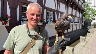 Ein Falkner mit einem Bussard auf der Hand.