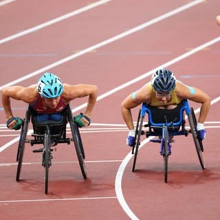 Behinderten Sportlerinnen fahren in ihren Rennrollstühlen um die Wette