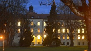 Das Bild zeigt das Krankenhaus Bad Waldsee bei Dunkelheit mit beleuchteten Zimmern.