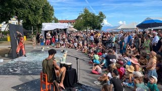 Künstler bemalen ein Bild live beim Kulturufer in Friedrichshafen. Viele Zuschauer sehen zu.