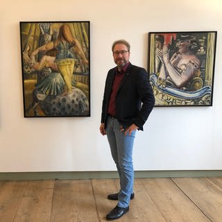 Kurator Michael Maurer vor Bildern von Paul Kleinschmidt auf Achberg