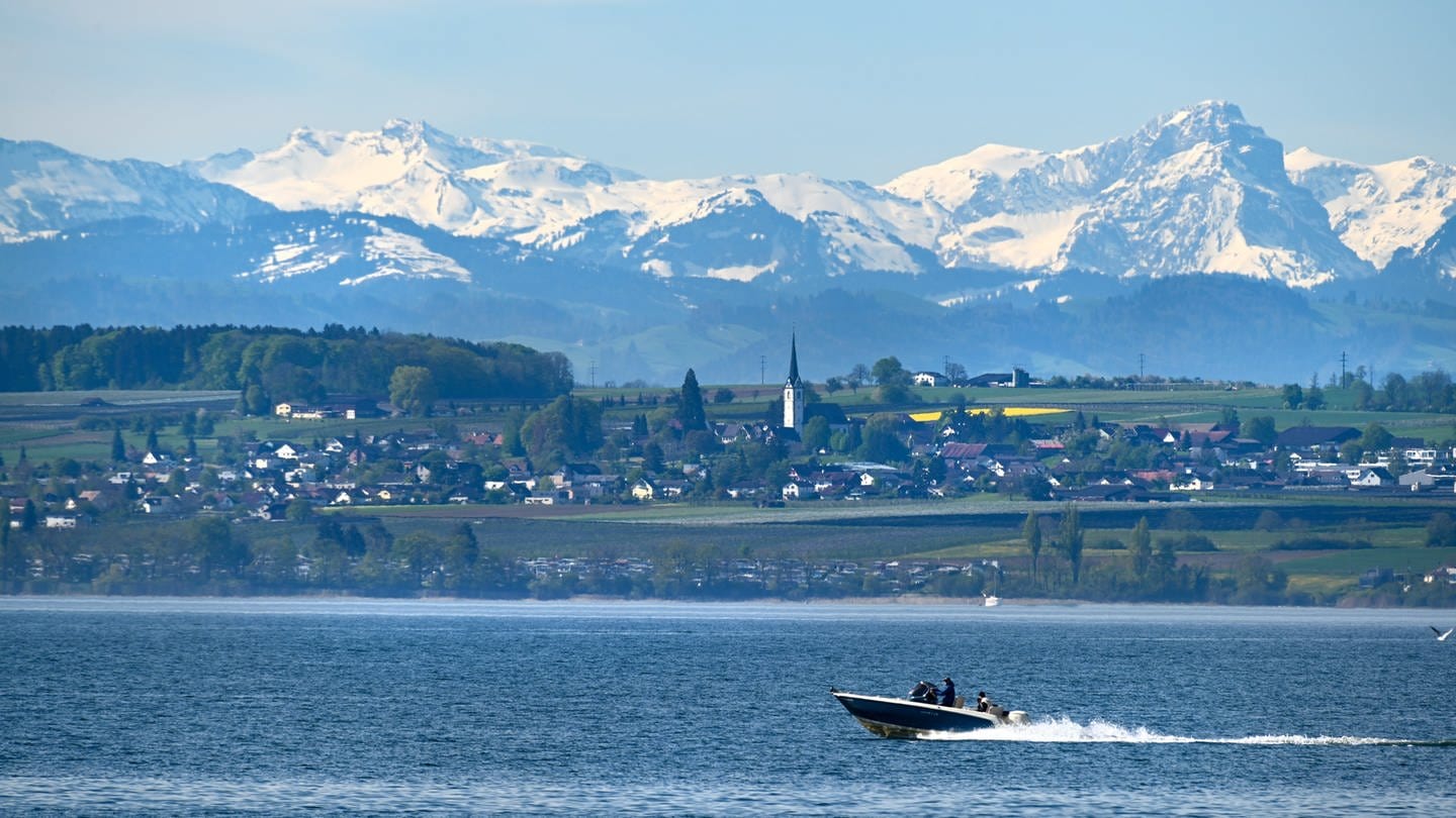 Ein Motorboot fährt auf dem Bodensee. Im Hintergrund sind die Schweizer Alpen zu sehen.