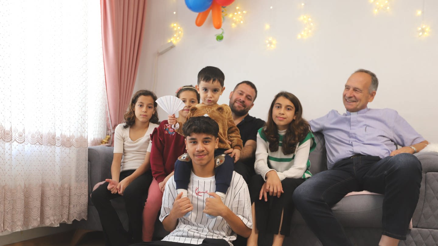 Auf einem Bild ist die Familie Hourie abgebildet mit dem kleinen Waisenjungen Mohammad.