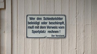 Ein Schild auf einem Fußballplatz warnt davor, den Schiedsrichter zu beleidigen