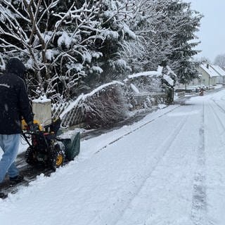 Erster Schnee im Allgäu am Wochenende, Mann fräst mit Schneefräse den Weg frei