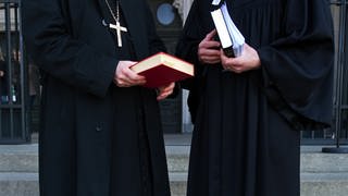 Zwei Geistliche unterhalten sich und halten eine Bibel in den Händen