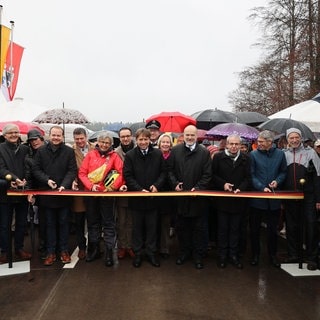 Poltikerinnen und Politiker durchschneiden ein Band zur Freigabe der neuen Brücke B32 Herfatz