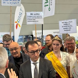 Özdemir wir bei seinem Besuch auf der Messe Fruchtwelt Bodensee in Friedrichshafen von Demonstranten begleitet