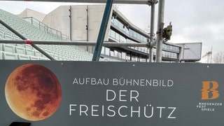 Ein Plakat informiert darüber, dass auf der Seebühne im Bodensee das Bühnenbild für "Freischütz" der Bregenzer Festspiele aufgebaut wird.