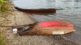 Zwei Teile eines Holzbootes am Seeufer