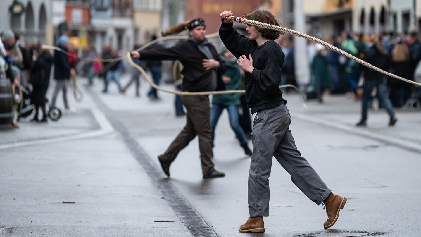 Narren schwingen in Überlingen am Bodensee ihre traditionellen Peitschen, die Karbatschen