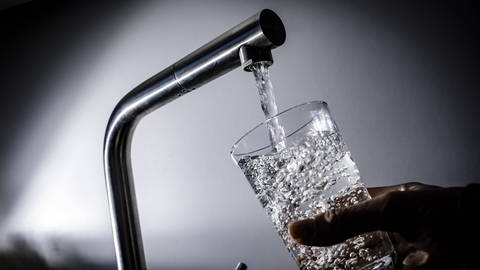 Wasser aus Wasserhahn läuft in Glas