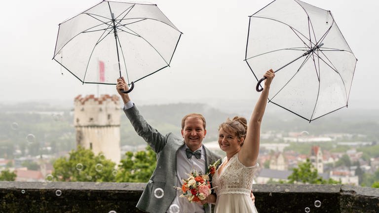 Brautpaar unter Regenschirmen