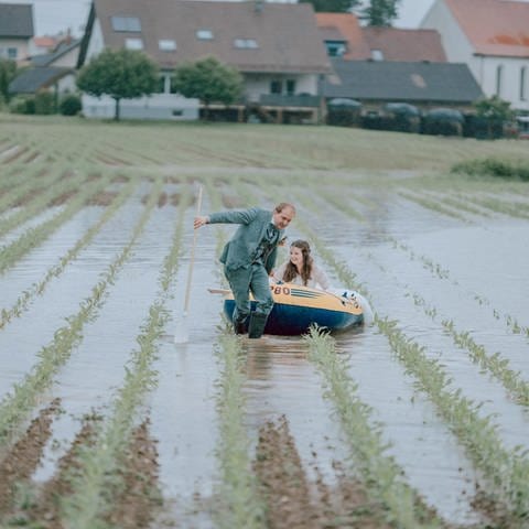 Das Brautpaar zieht das Schlauchboot auf ein überflutetes Feld.