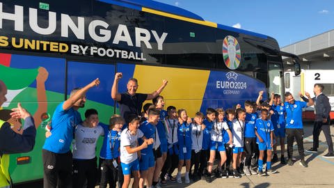 Ungarische Spieler und Kinder posieren vor Tourbus