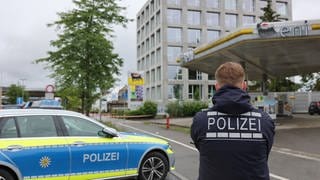 Ein Polizeiauto und ein Polizist stehen vor Tankstellengelände in Konstanz