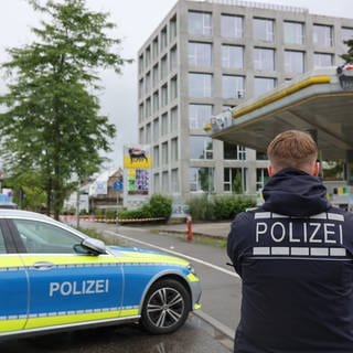 Ein Polizeiauto und ein Polizist stehen vor Tankstellengelände in Konstanz