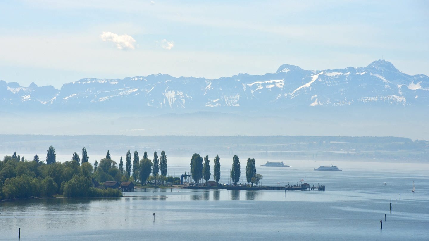Zwei Fähren fahren bei Meersburg vor dem Panorama der Schweizer Alpen über den Bodensee.