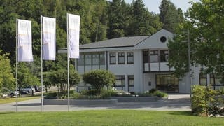 Ein Gebäude der Kliniken Schmieder in Allensbach, im Vordergrund Fahnen mit dem Unternehmenslogo (Archivbild).