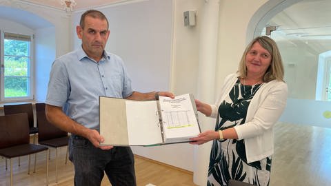Herbert Birk von der Initiative gegen den Turm im Wurzacher Ried übergibt die gesammelten Unterschriften an Bürgermeisterin Alexandre Scherer (CDU).