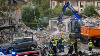 Rettungskräfte arbeiten an der Unglücksstelle. In Bayern ist der Polizei zufolge nach einer Explosion ein Reiheneckhaus eingestürzt.