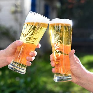 Zwei Personen stoßen mit Bier an. 