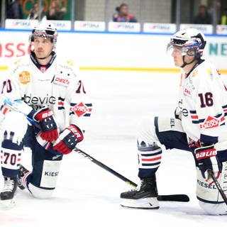 Zwei Eishockeyspieler knien auf der Eisfläche.