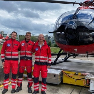 Drei Männer vor einem Rettungshubschrauber