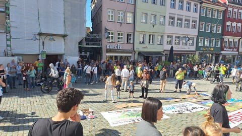 Menschen auf dem Marienplatz in Ravensburg und bunte Transparente auf dem Boden