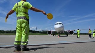 Ein Mitarbeiter des Bodensee-Airports in Friedrichshafen weist ein Passagierflugzeug zu seinem Platz. Am Flughafen am Bodensee landen immer weniger Maschinen.