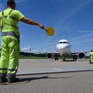 Ein Mitarbeiter des Bodensee-Airports in Friedrichshafen weist ein Passagierflugzeug zu seinem Platz. Am Flughafen am Bodensee landen immer weniger Maschinen.