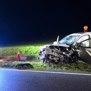 Ein zerstörtes Auto steht nach einem schweren Unfall am Straßenrand, daneben ein Feuerwehrauto. Bei dem Frontal-Crash bei Frickingen im Bodenseekreis wurden zwei Menschen lebensgefährlich verletzt 