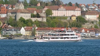 Ein Ausflugsschiff mit Touristen fährt auf dem Bodensee an Meersburg vorbei.