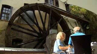 Das Restaurant Bibermühle mit großem Mühlrad auf der Terrasse