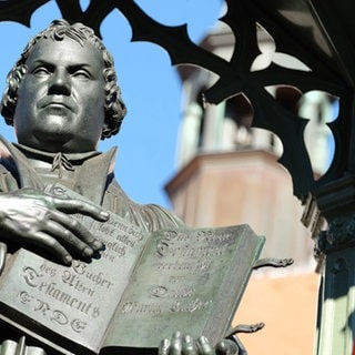 Links ist das Lutherdenkmal in Wittenberg zu sehen, rechts ein geschnitzter Kürbis