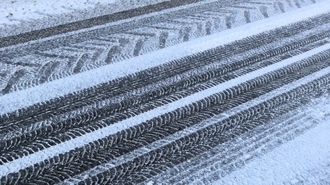 Autoreifen-Profile auf winterlicher Straße.