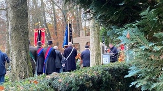 Eine Fahnenabordnung steht auf dem Friedhof in Bad Waldsee vor dem Denkmal für die Gefallenen in beiden Weltkriegen.