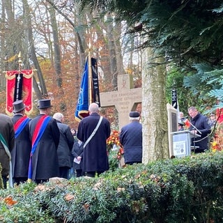 Eine Fahnenabordnung steht auf dem Friedhof in Bad Waldsee vor dem Denkmal für die Gefallenen in beiden Weltkriegen.