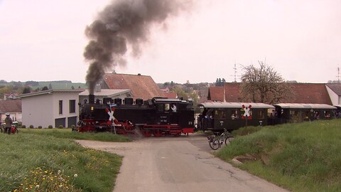 Eine historische Schmalspurbahn fährt durch die Landschaft