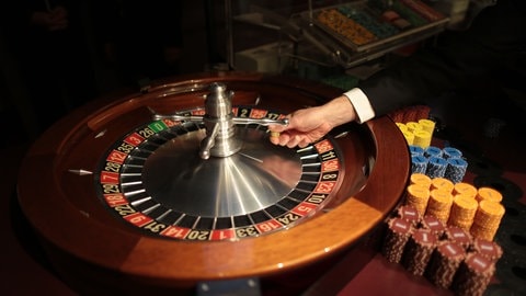 Ein Croupier im Spielcasino, auch Dealer genannt, wirft eine Kugel in das Roulette