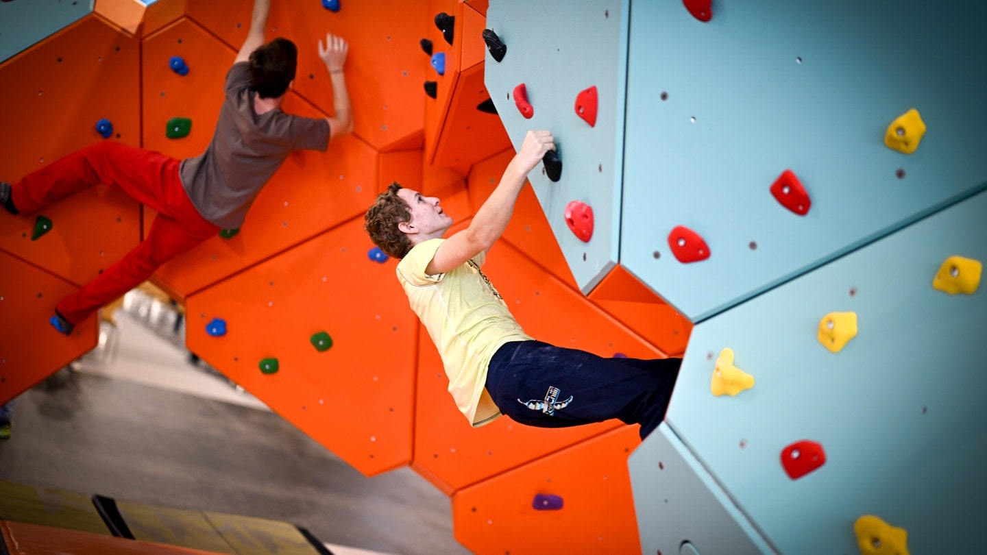 Zwei junge Männer hängen in einer Kletterwand. Ums Klettern geht es bei der Messe Vertical Pro in Friedrichshafen.