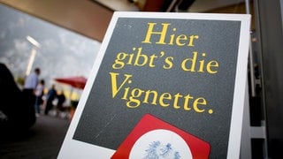 Ein Schild mit der Aufschrift "Hier gibt's die Vignette." ist an einer Autobahnraststätte