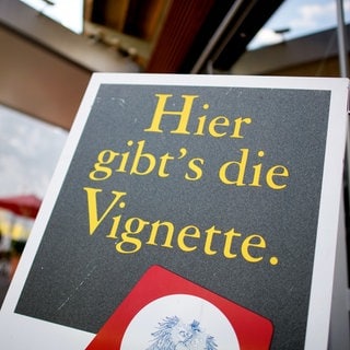 Ein Schild mit der Aufschrift "Hier gibt's die Vignette." ist an einer Autobahnraststätte