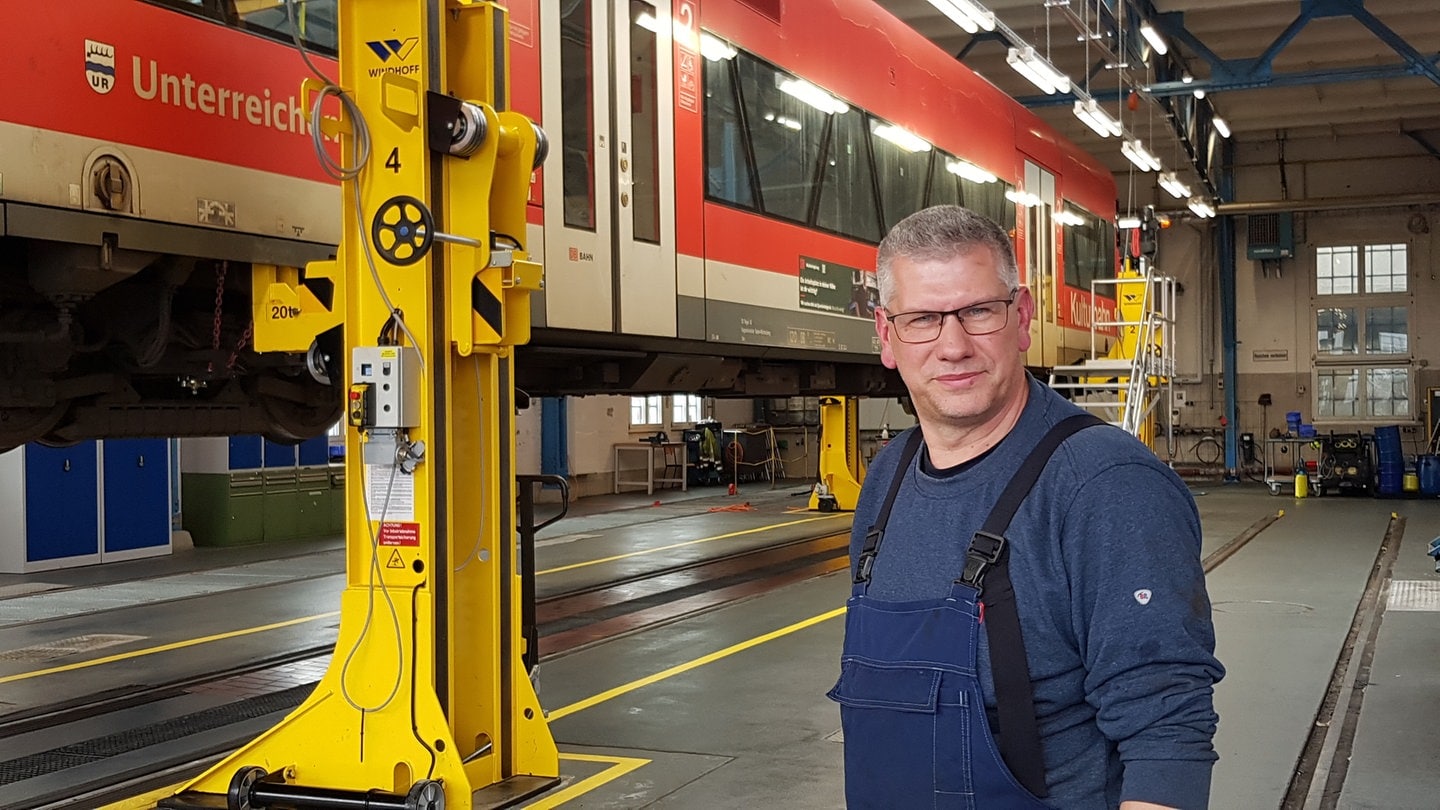 Hans-Jürgen Richter vor einem aufgebockten Zug in der Wartungshalle in Friedrichshafen