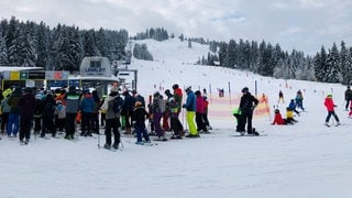 Menschen stehen in einer Schlange vor einem Skilift im Skigebiet Bödele in Vorarlberg