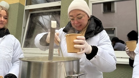 Eine Studentin schenkt Suppe an die Obdachlosen in Ravensburg aus.