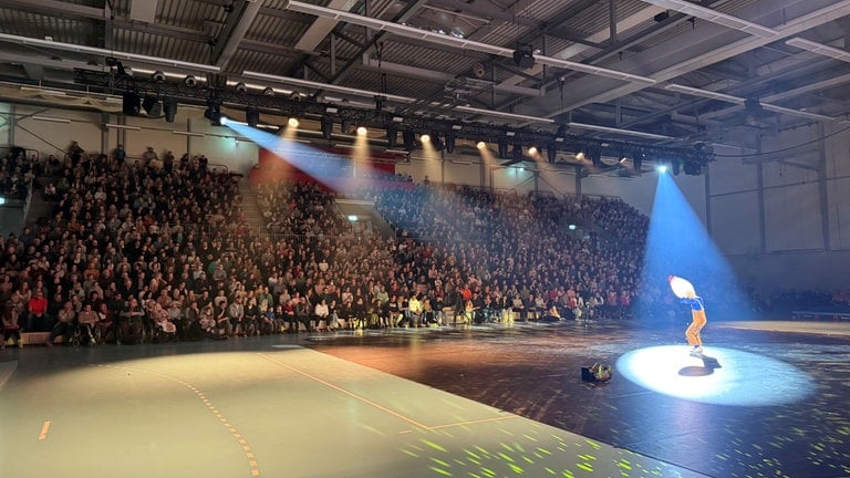 Künstler in Verkleidung im Scheinwerferlicht vor Publikum in Schänzle-Halle